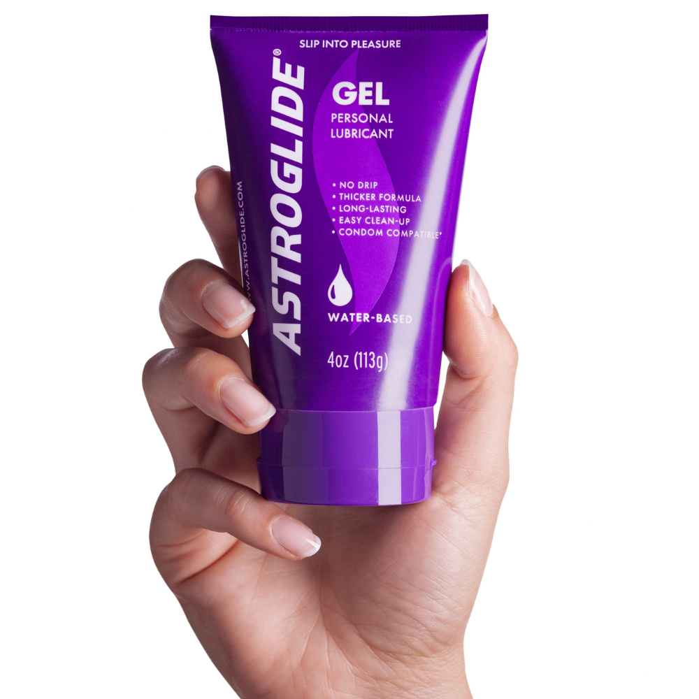 Hand holding a tube of Astroglide Gel water-based personal lubricant on a white background