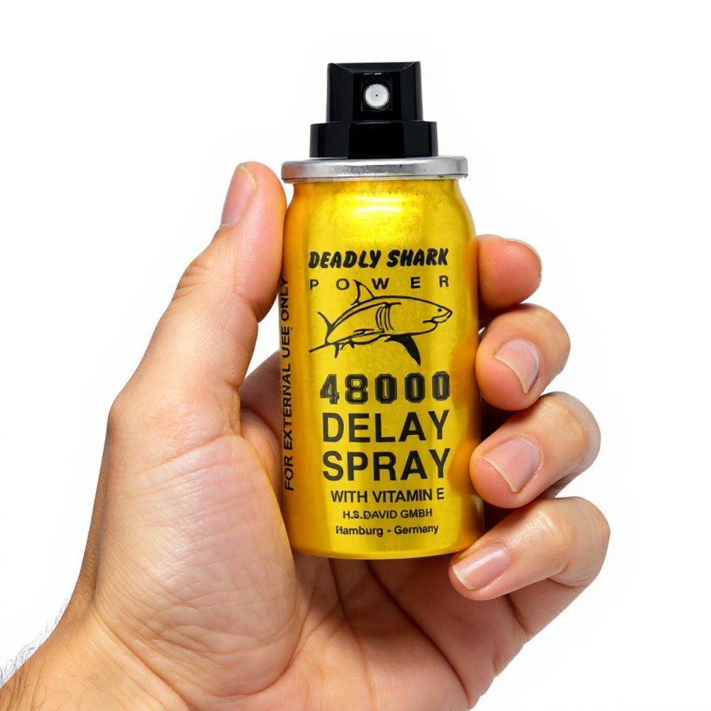 Deadly Shark Power 48000 Delay Spray with Vitamin E held in hand, gold bottle with shark logo