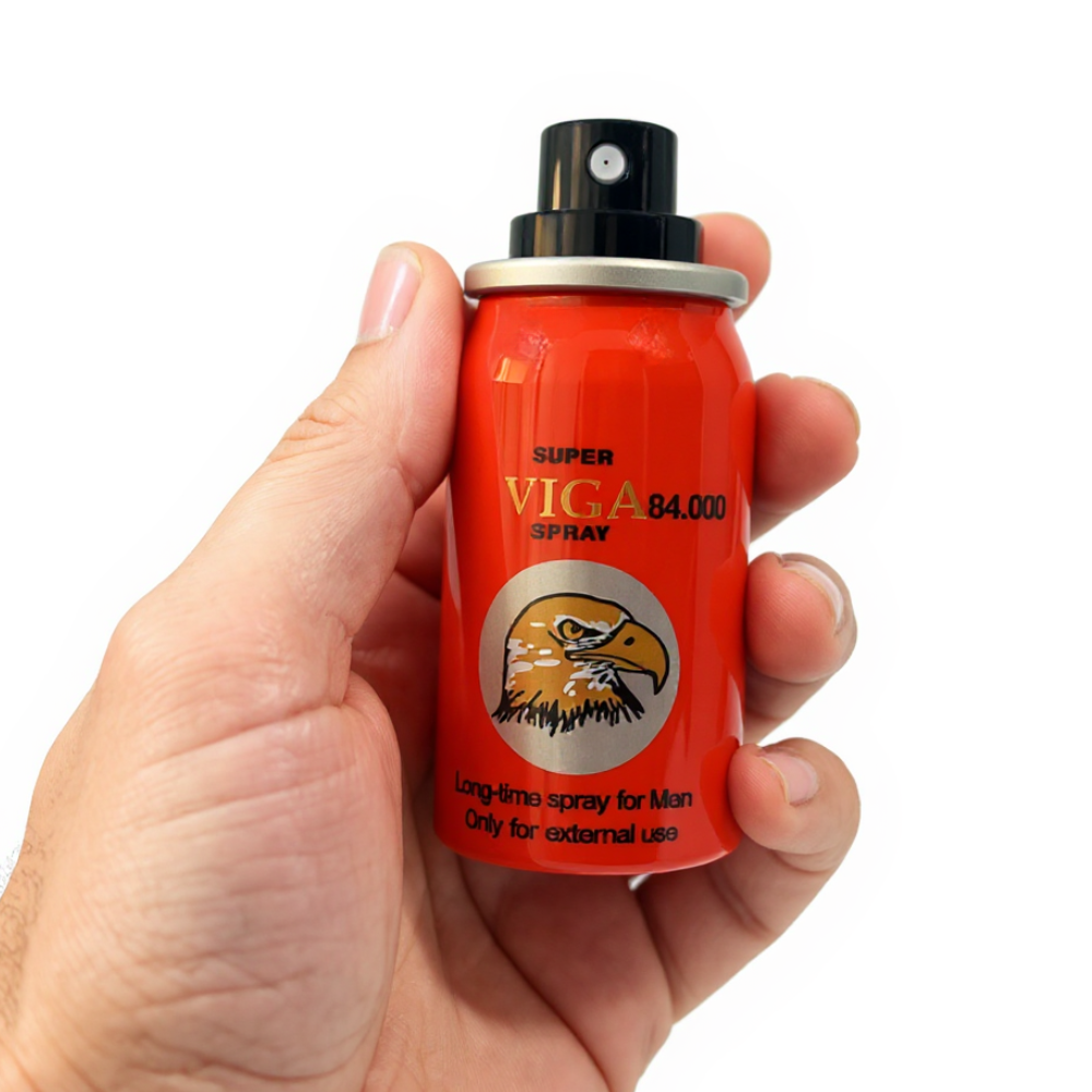 Hand holding Super Viga 84000 Delay Spray for men, red bottle with eagle logo and black nozzle
